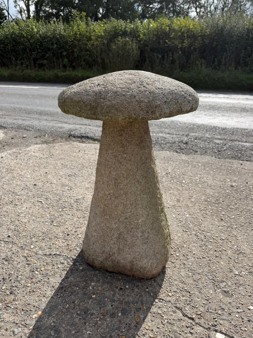 A hand-hewn grey Cornish granite staddle stone with a tapered base and rounded cap resting on a flat surface. View II