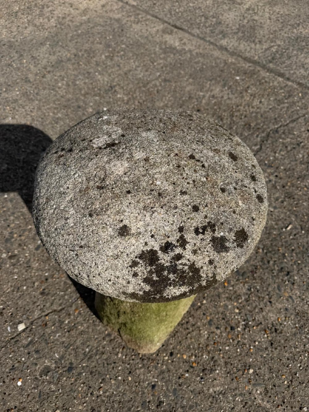 A hand-hewn grey Cornish granite staddle stone with a tapered base and rounded cap resting on a flat surface. View III