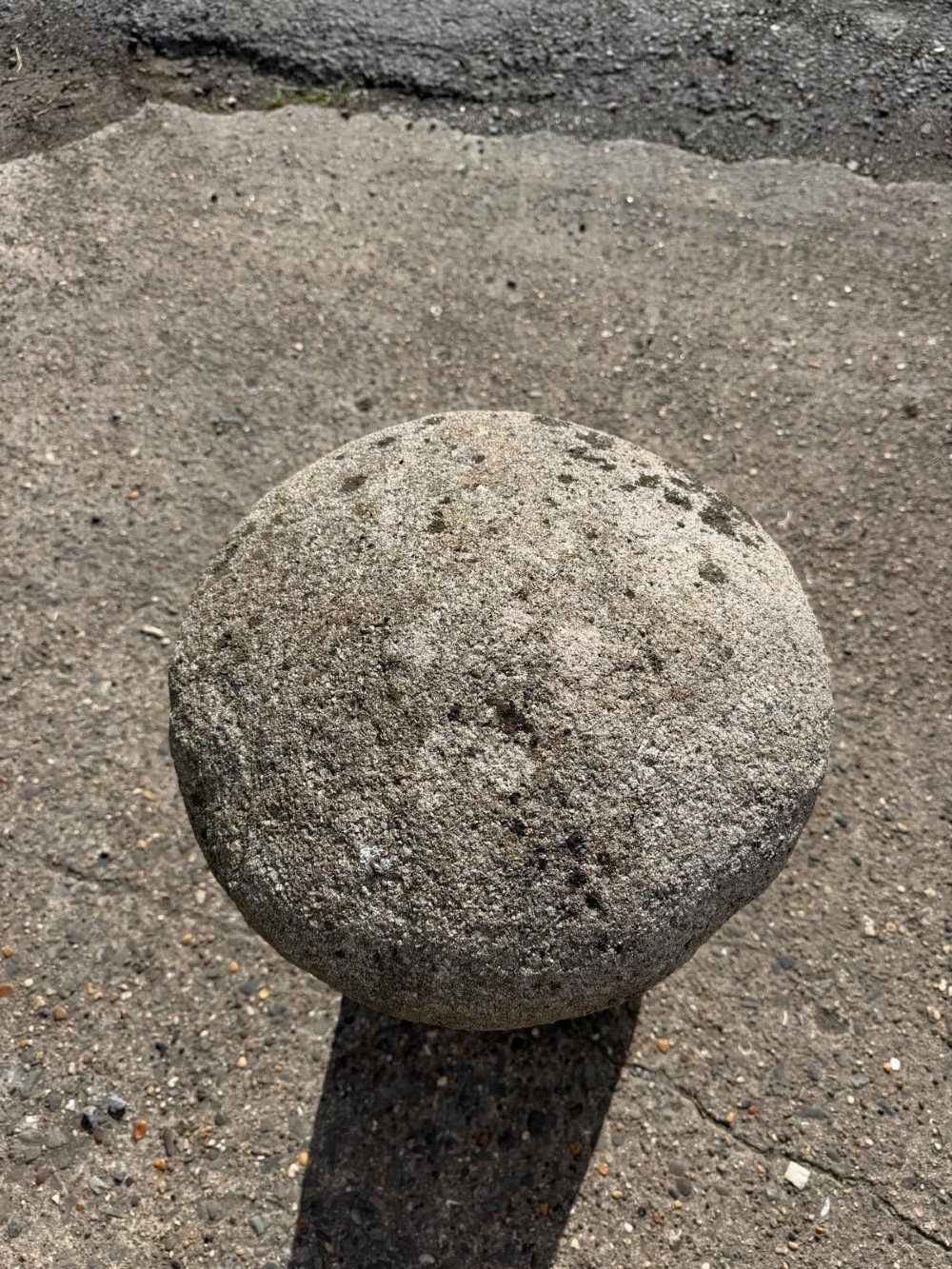 A hand-hewn grey Cornish granite staddle stone with a tapered base and rounded cap resting on a flat surface. View IV