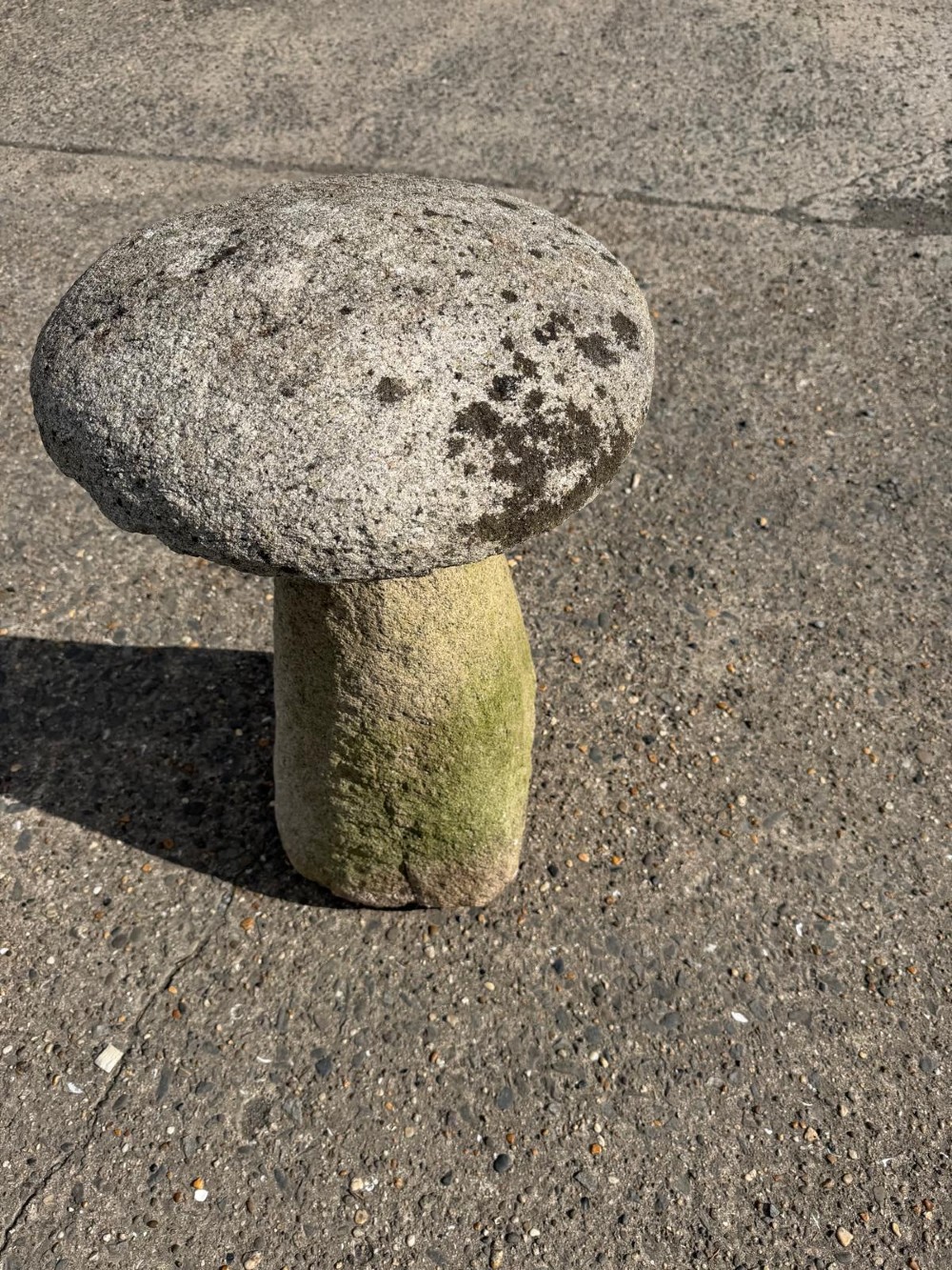 A hand-hewn grey Cornish granite staddle stone with a tapered base and rounded cap resting on a flat surface. View VI