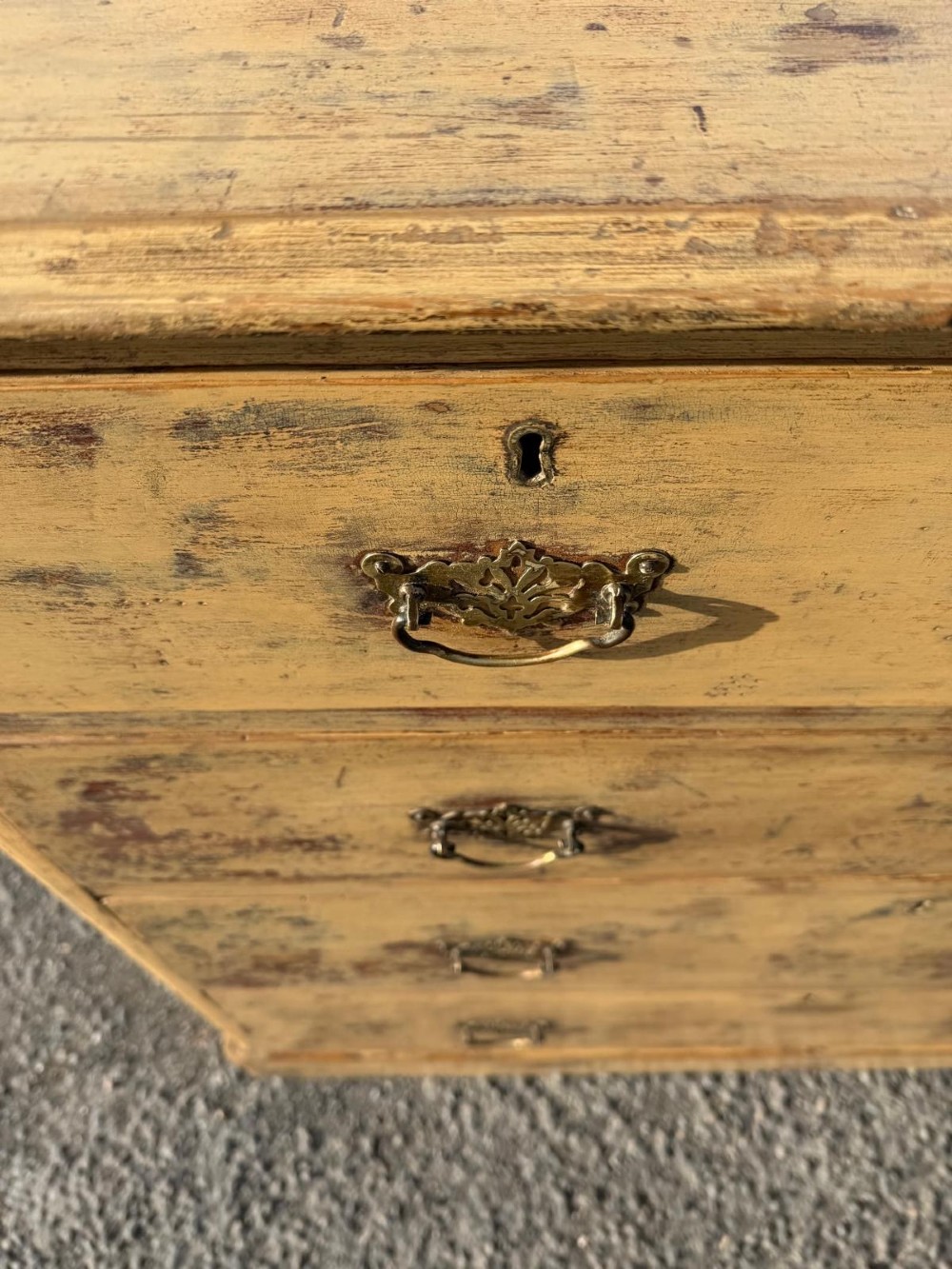 A Victorian painted pine chest of drawers in a two over three drawer layout with brass drop handles and distressed original yellow paint. View III