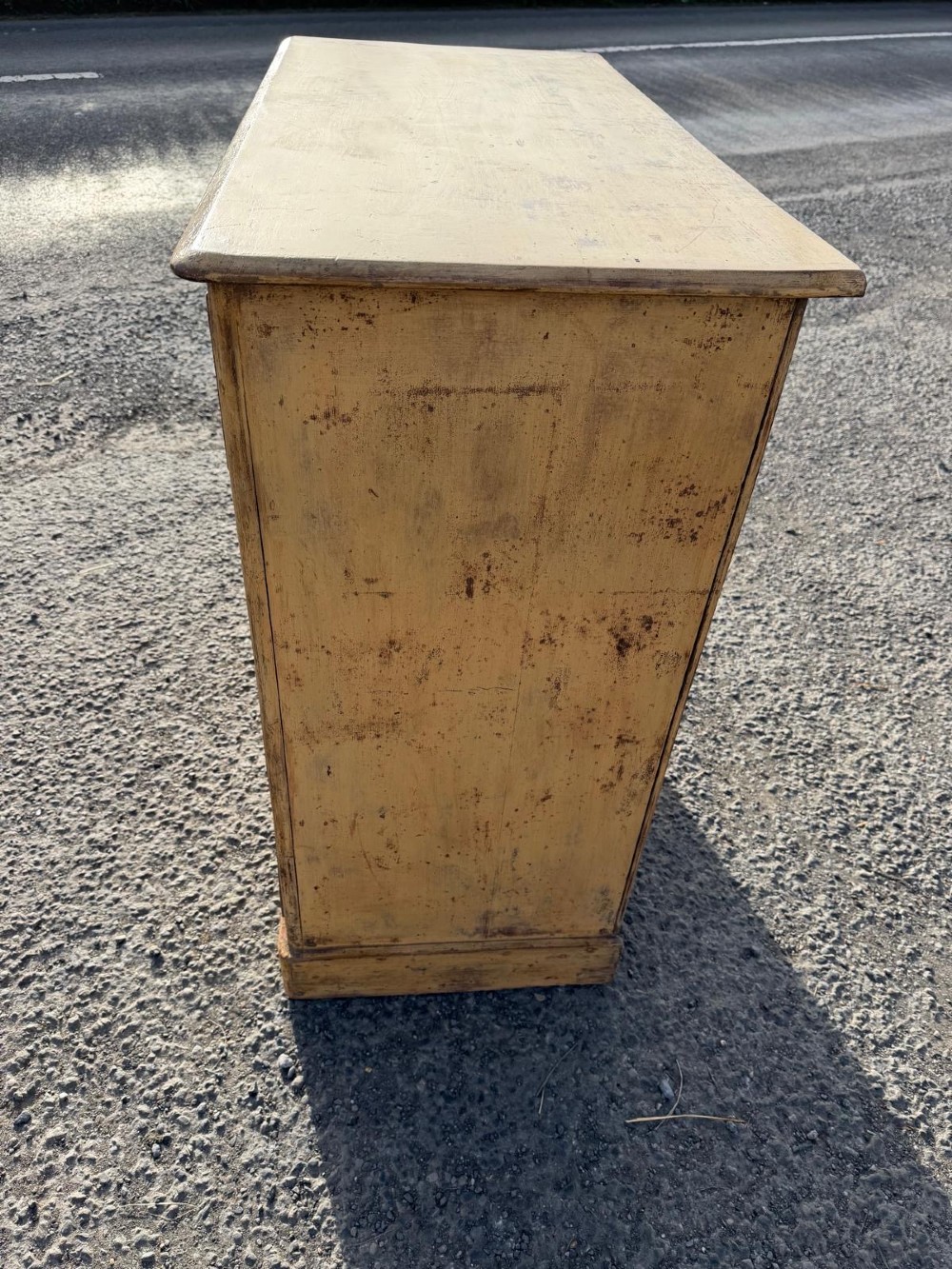 A Victorian painted pine chest of drawers in a two over three drawer layout with brass drop handles and distressed original yellow paint. View IV
