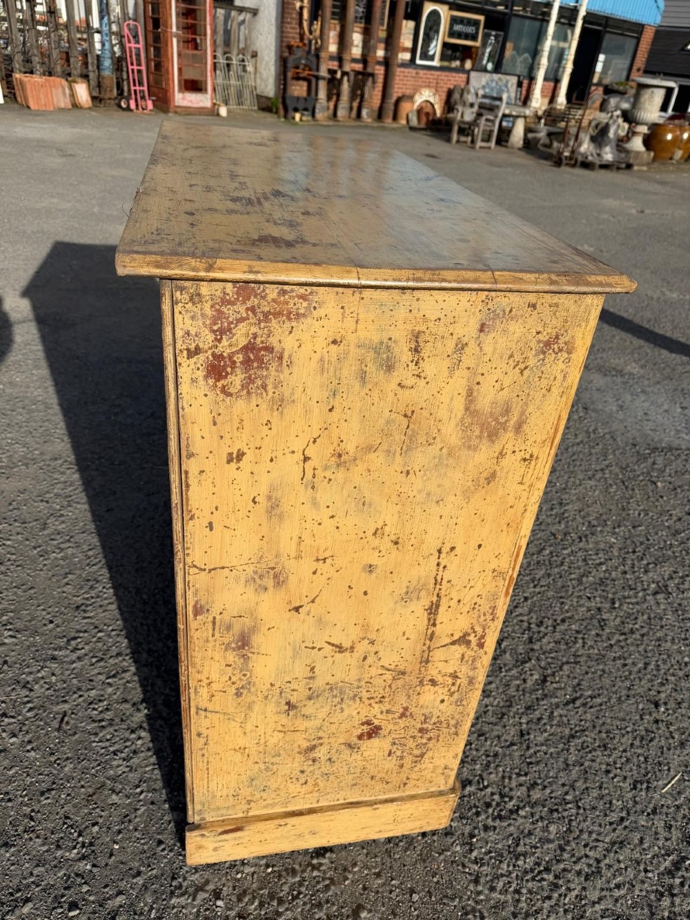 A Victorian painted pine chest of drawers in a two over three drawer layout with brass drop handles and distressed original yellow paint. View V