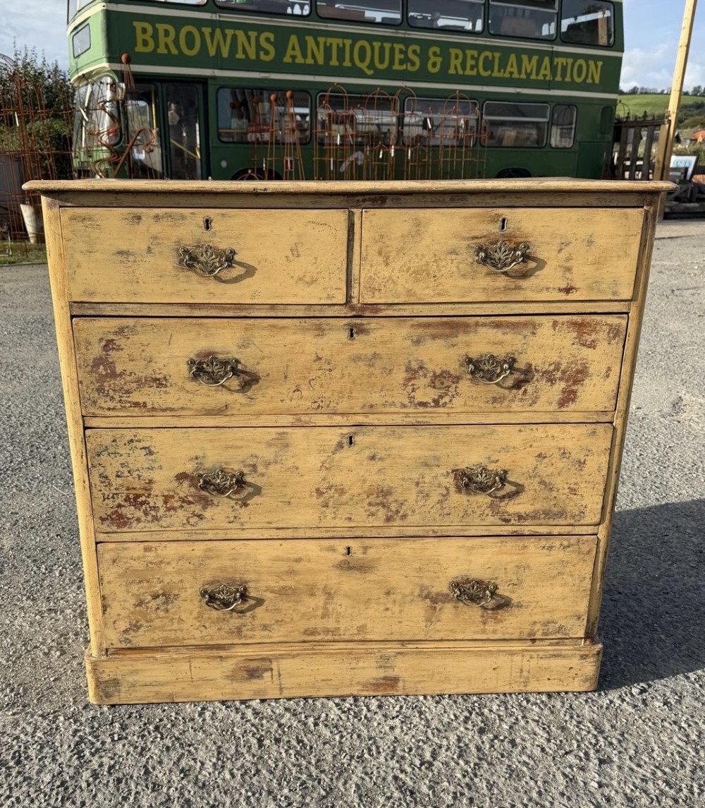 A Victorian painted pine chest of drawers in a two over three drawer layout with brass drop handles and distressed original yellow paint. View II