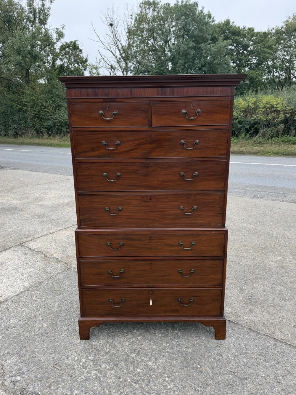A tall Georgian mahogany chest on chest featuring eight drawers with brass swan-neck handles, resting on bracket feet.