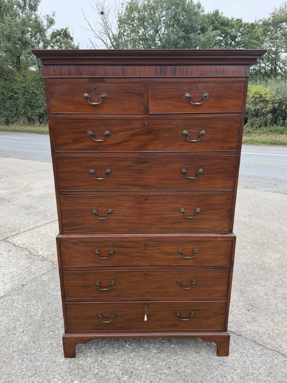 A tall Georgian mahogany chest on chest featuring eight drawers with brass swan-neck handles, resting on bracket feet. View II