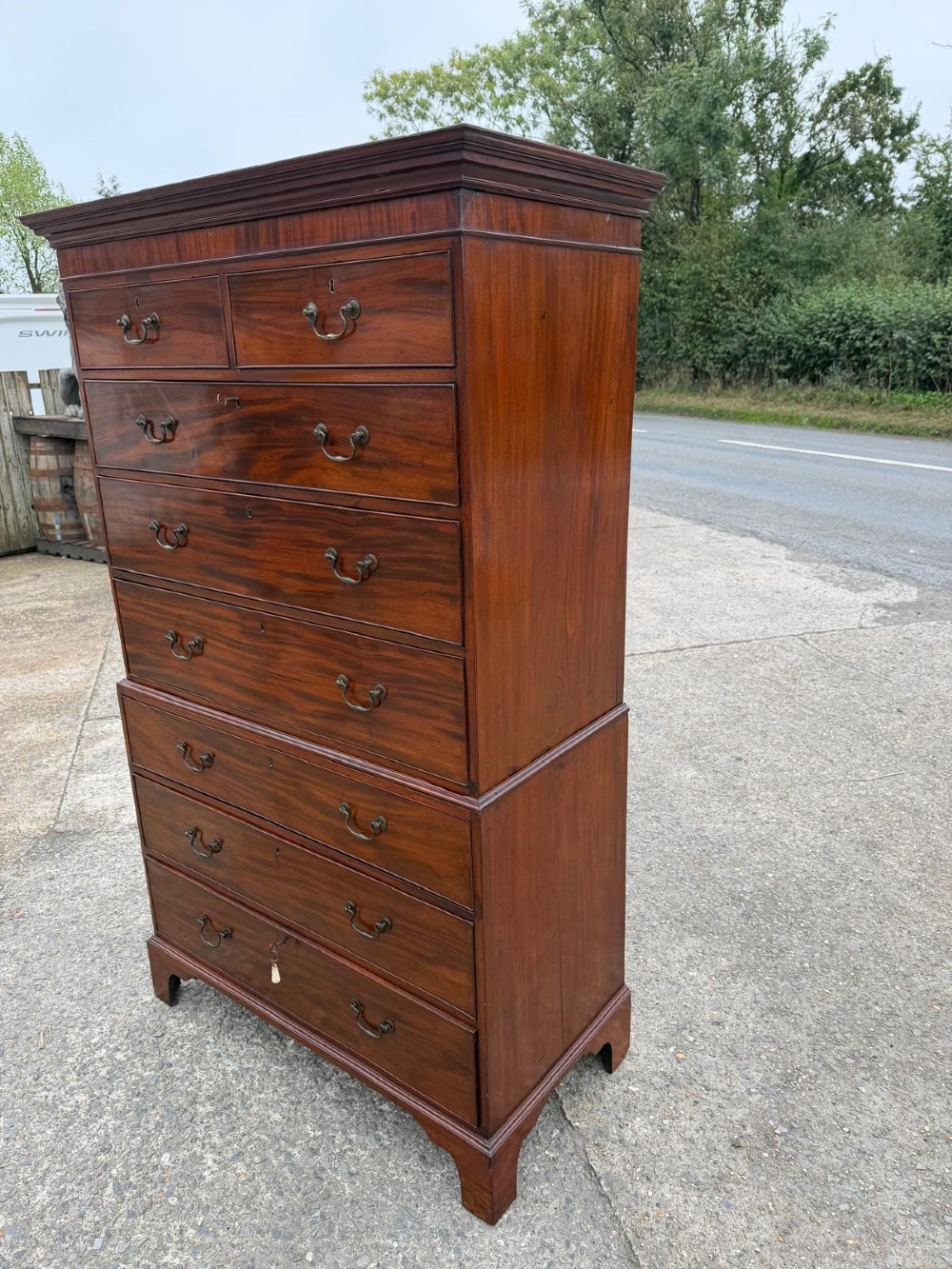 A tall Georgian mahogany chest on chest featuring eight drawers with brass swan-neck handles, resting on bracket feet. View IV