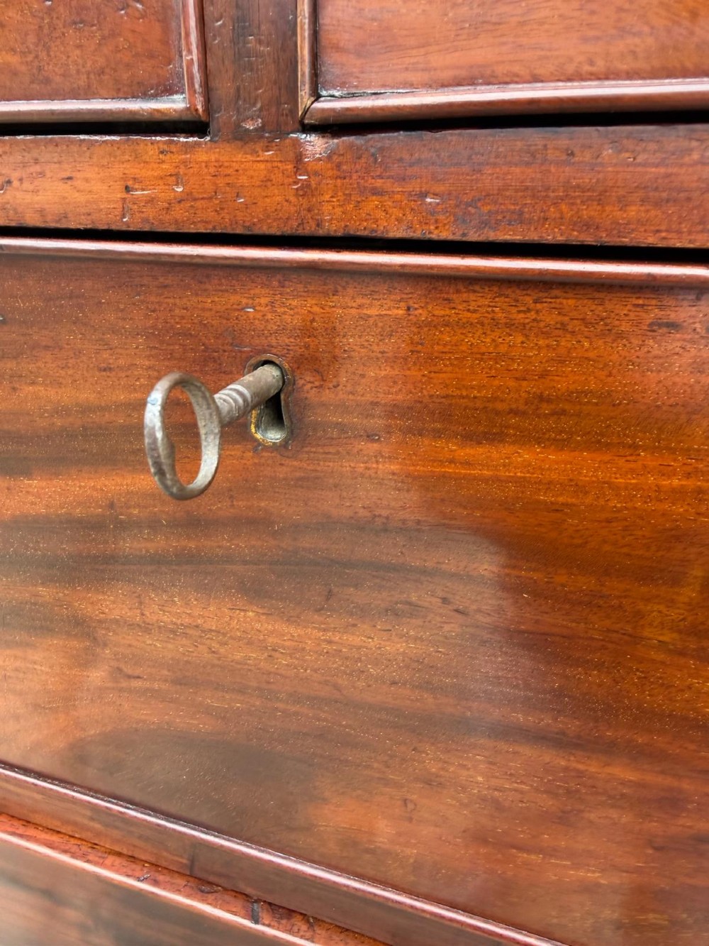 A tall Georgian mahogany chest on chest featuring eight drawers with brass swan-neck handles, resting on bracket feet. View VI
