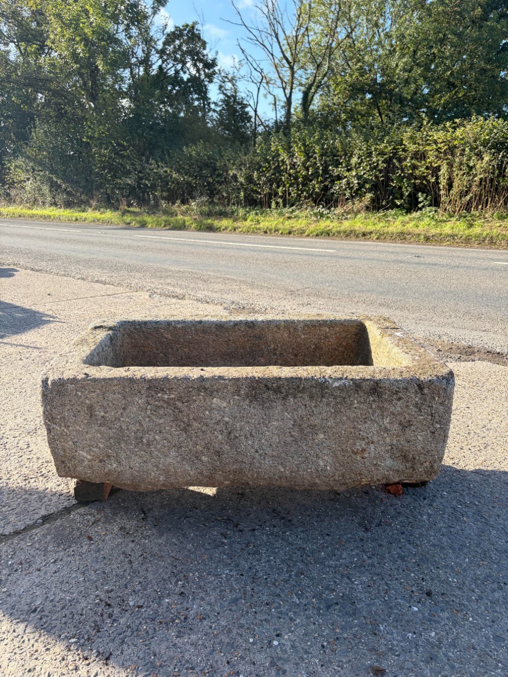 A heavy rectangular antique Cornish granite trough featuring a hand-chiselled rough stone exterior and carved basin.