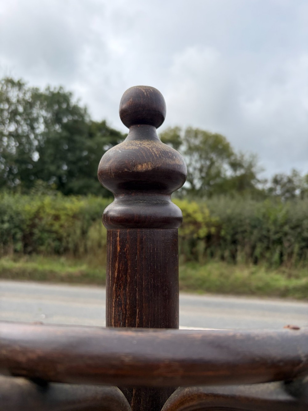 A dark brown bentwood coat stand with curved upper hooks, central accessory loops, a turned finial, and four splayed legs. View II