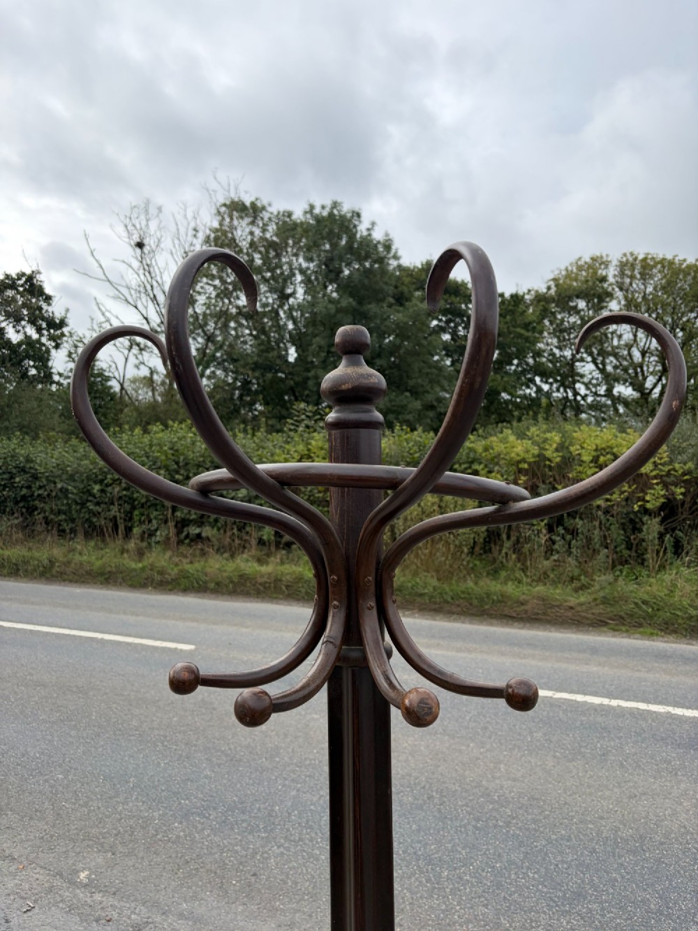 A dark brown bentwood coat stand with curved upper hooks, central accessory loops, a turned finial, and four splayed legs. View IV