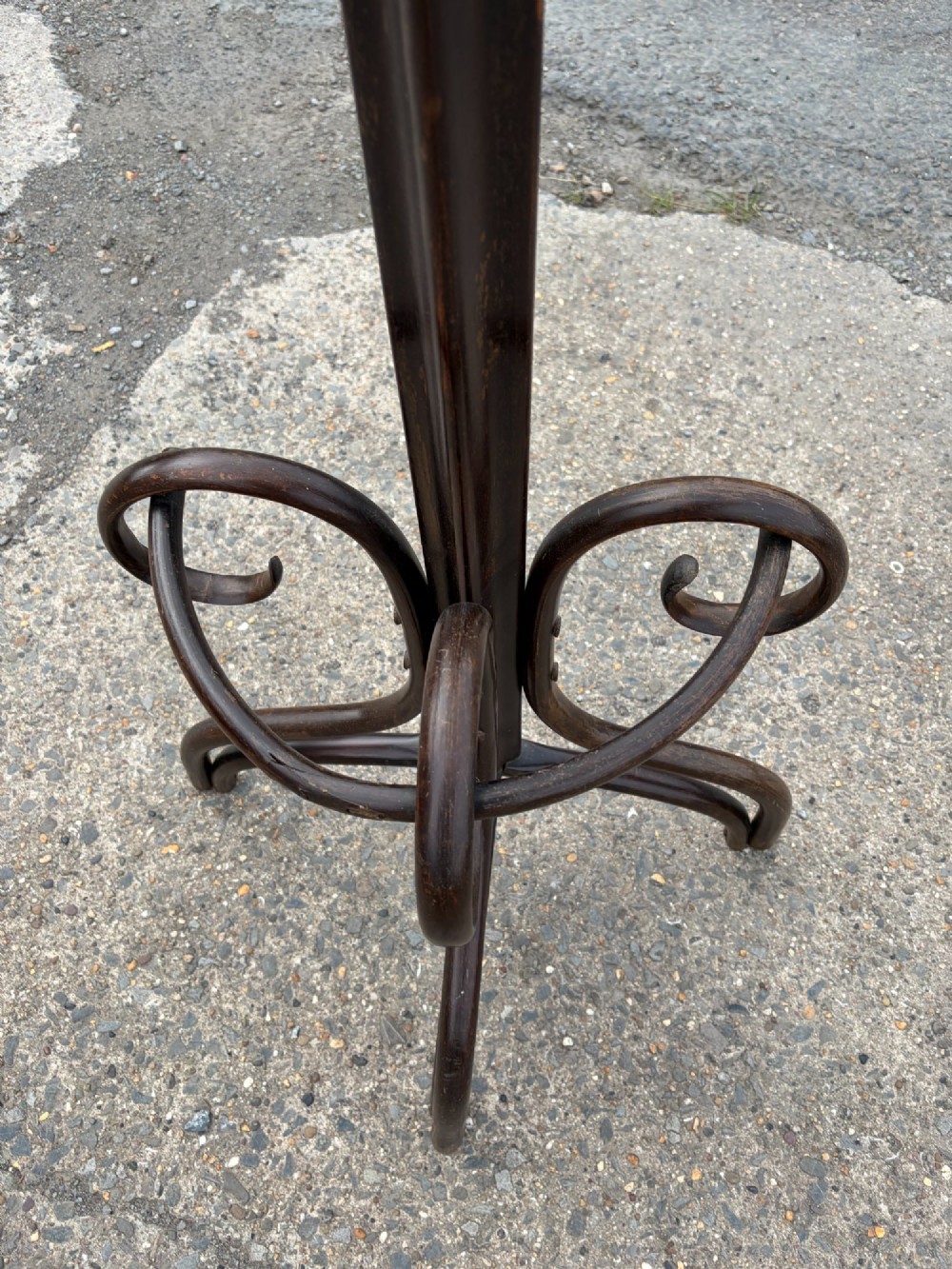 A dark brown bentwood coat stand with curved upper hooks, central accessory loops, a turned finial, and four splayed legs. View VI