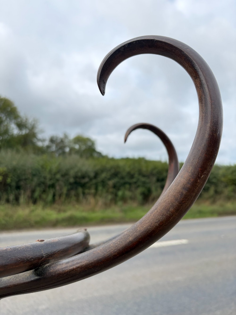 A dark brown bentwood coat stand with curved upper hooks, central accessory loops, a turned finial, and four splayed legs. View VIII