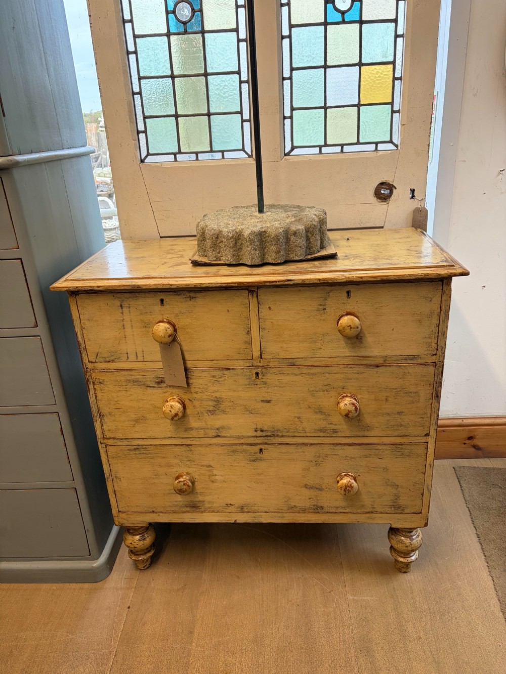 A Victorian painted pine chest of drawers with a two over two drawer configuration, turned wooden handles, and turned feet.