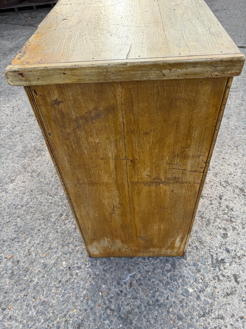 A late Victorian pine dresser base featuring a distressed ochre and green painted finish, three upper drawers, and recessed panel cupboard doors with wooden handles. View III