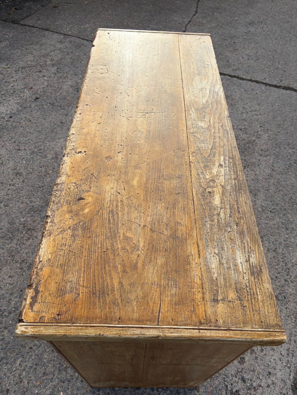 A late Victorian pine dresser base featuring a distressed ochre and green painted finish, three upper drawers, and recessed panel cupboard doors with wooden handles. View IV