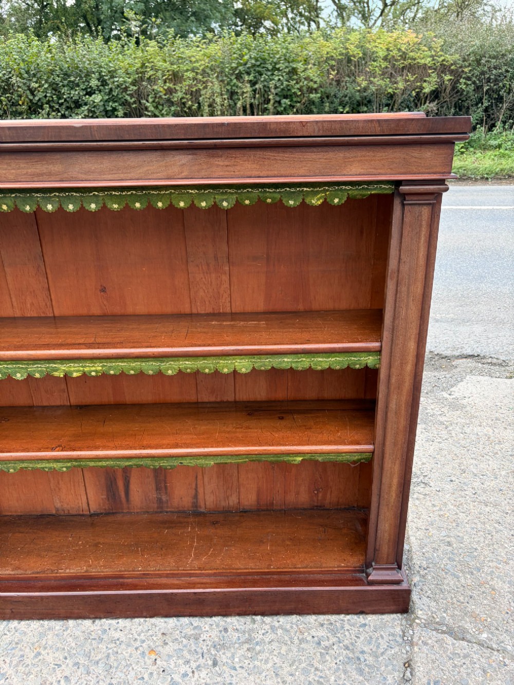 A matching pair of low, open-front early Victorian mahogany bookcases featuring green scalloped leather dust flaps along the shelf edges. View III