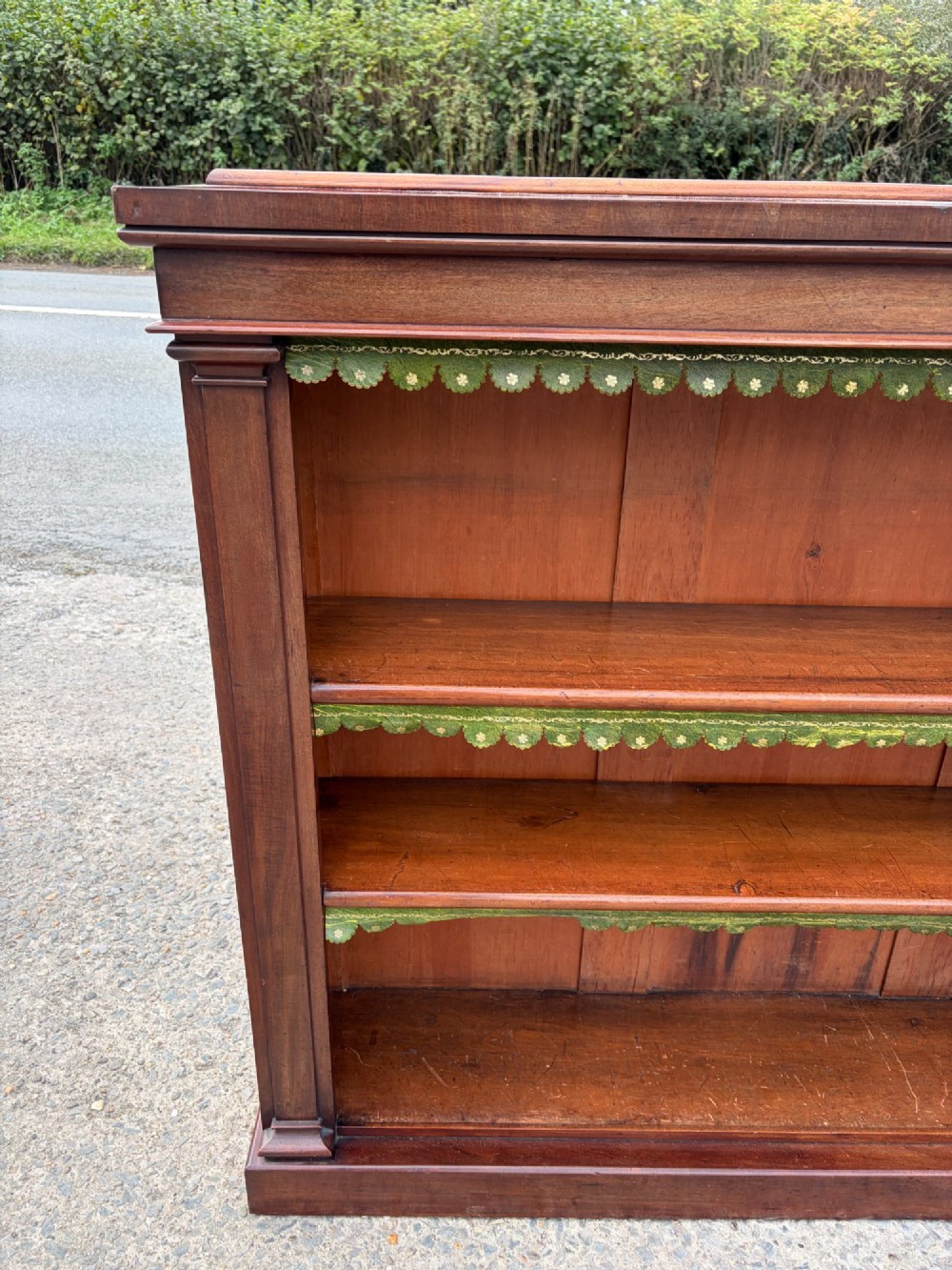 A matching pair of low, open-front early Victorian mahogany bookcases featuring green scalloped leather dust flaps along the shelf edges. View IV