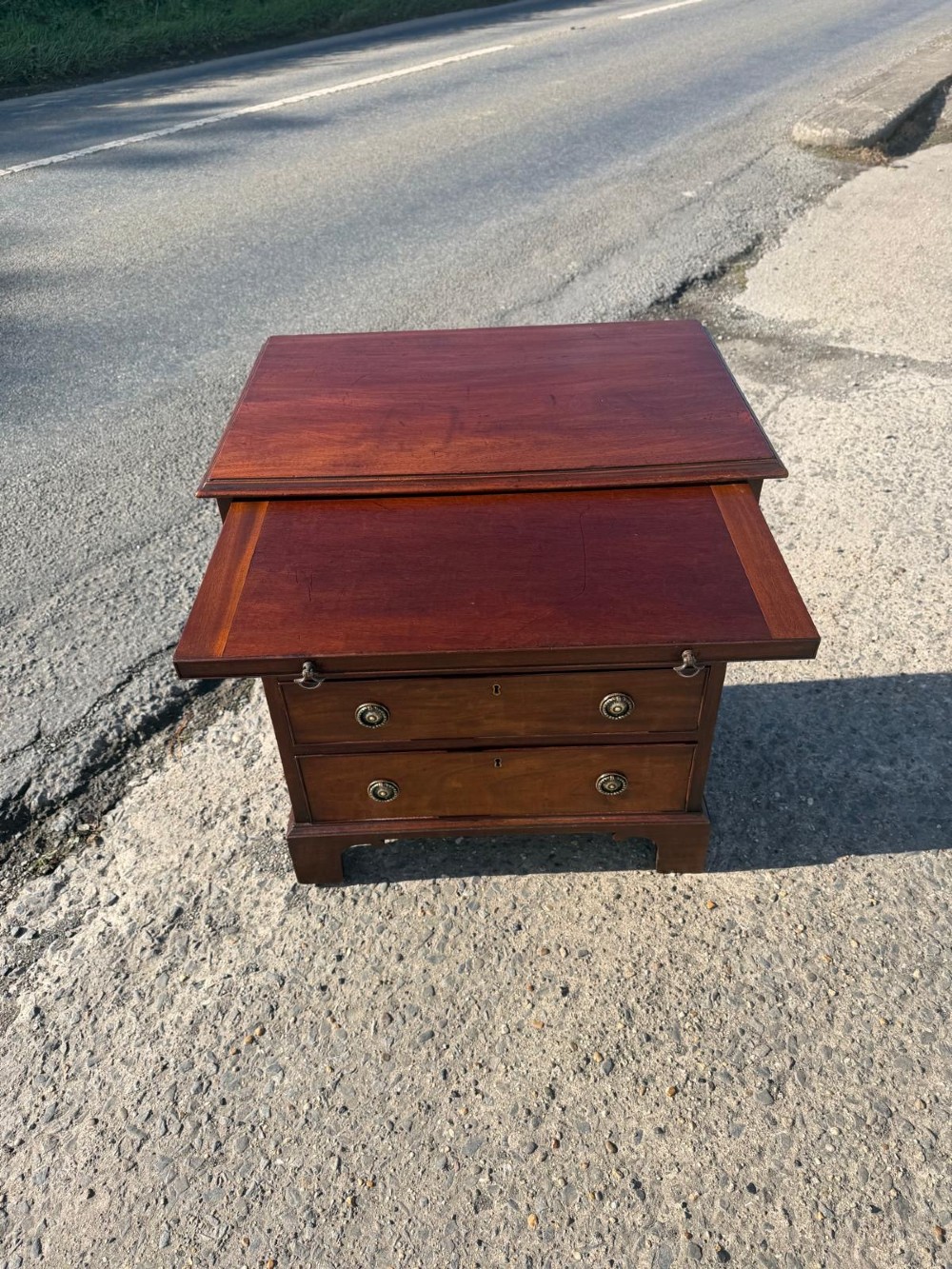 An antique Georgian mahogany bachelors chest featuring four graduated drawers with brass handles, a pull-out brushing slide, and bracket feet. View II