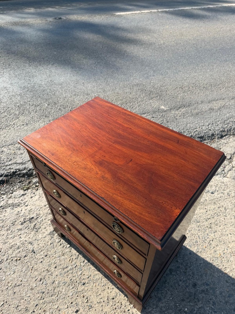 An antique Georgian mahogany bachelors chest featuring four graduated drawers with brass handles, a pull-out brushing slide, and bracket feet. View V