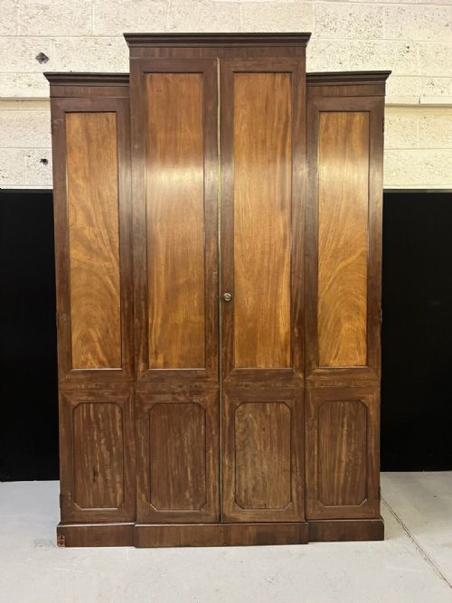 fig 1. A large mahogany breakfront wardrobe featuring four panelled doors with flame mahogany veneers and stepped moulded cornices.