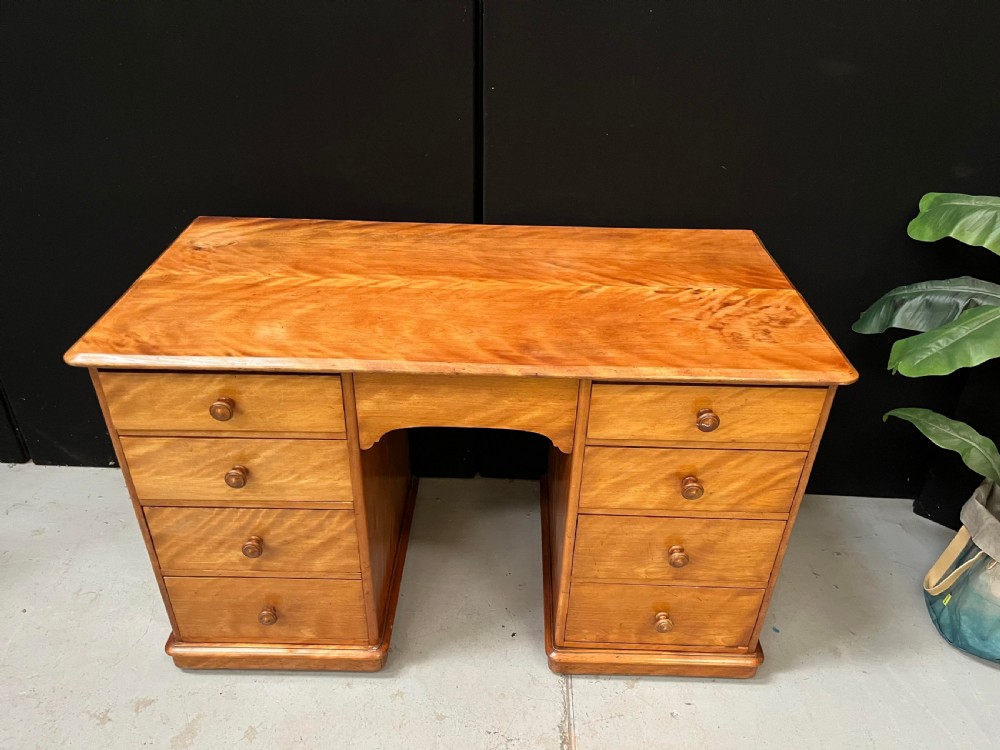 A Victorian satin birch pedestal writing desk featuring eight drawers with turned wooden knobs and an arched central kneehole. View II