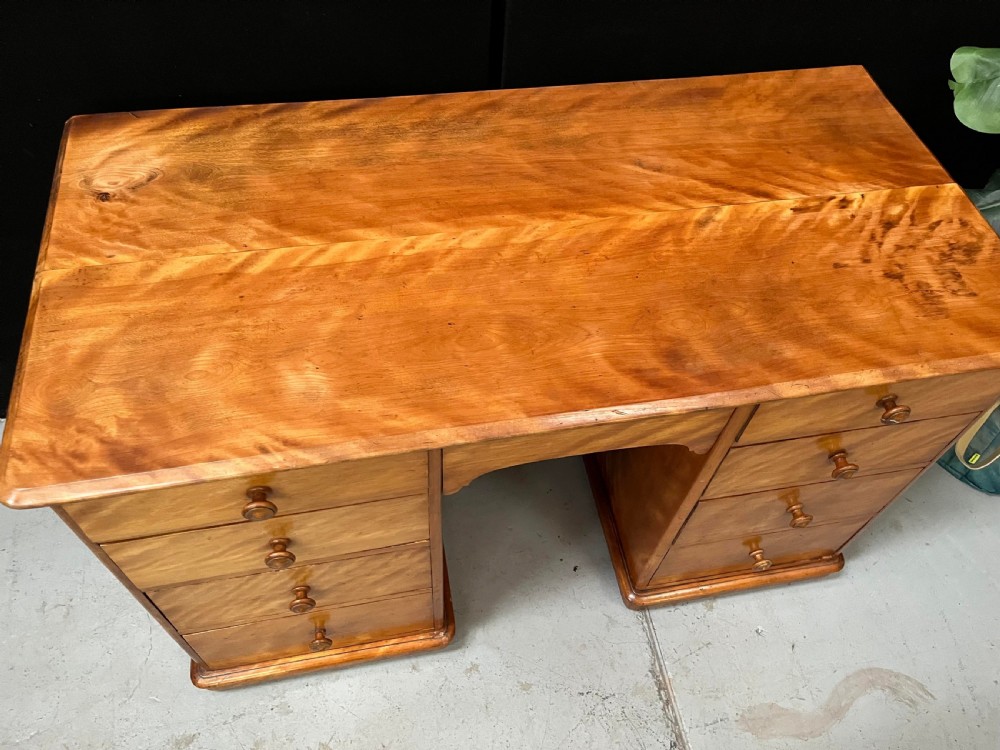 A Victorian satin birch pedestal writing desk featuring eight drawers with turned wooden knobs and an arched central kneehole. View VIII