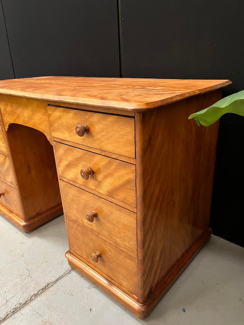 A Victorian satin birch pedestal writing desk featuring eight drawers with turned wooden knobs and an arched central kneehole. View X