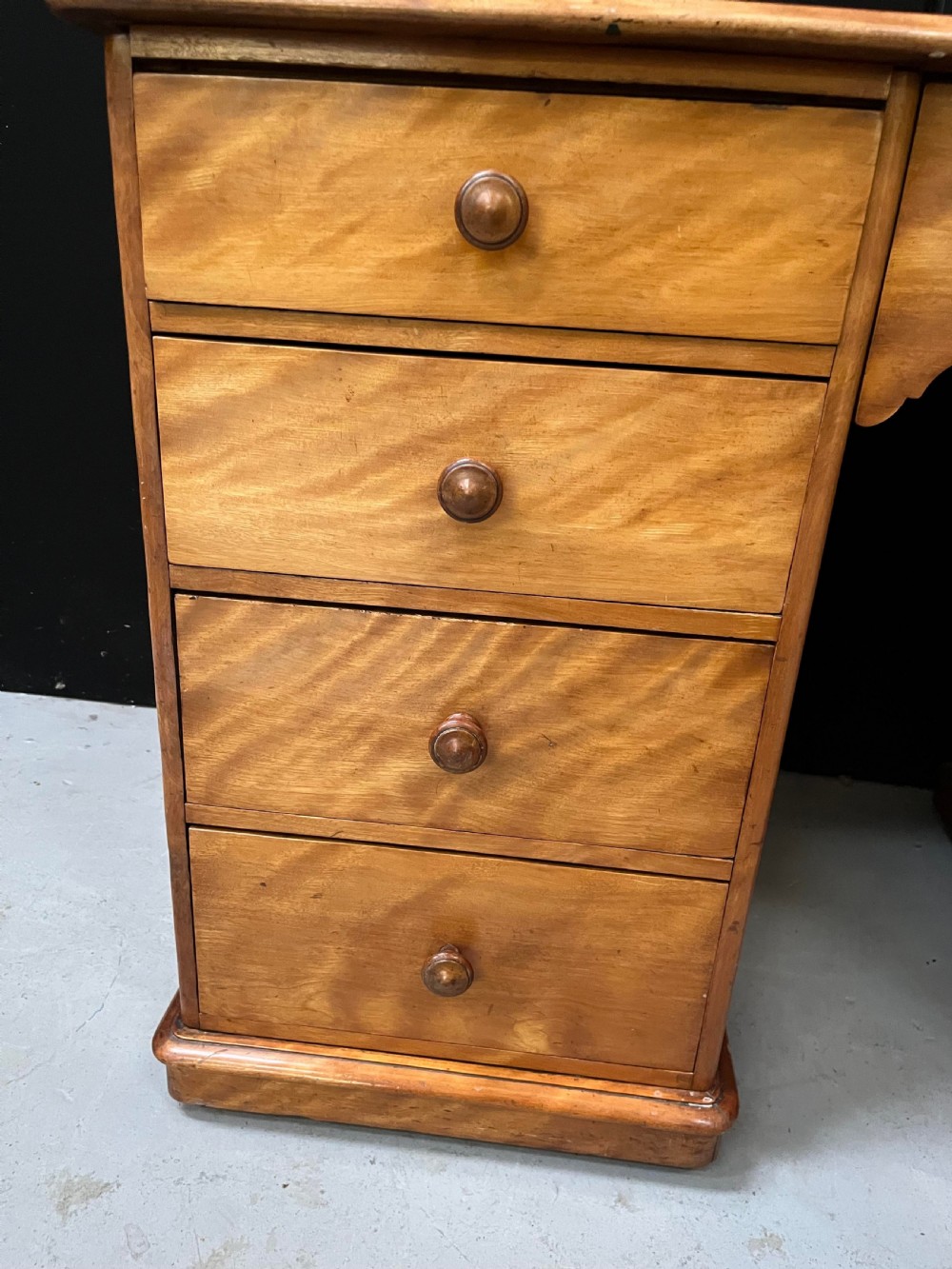A Victorian satin birch pedestal writing desk featuring eight drawers with turned wooden knobs and an arched central kneehole. View XI