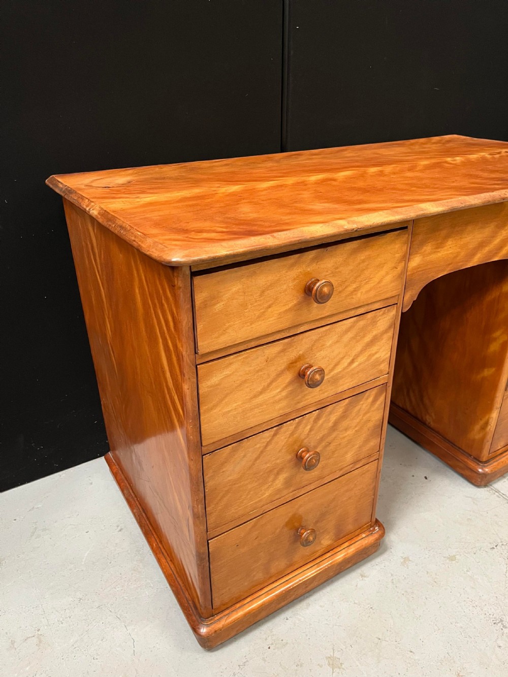 A Victorian satin birch pedestal writing desk featuring eight drawers with turned wooden knobs and an arched central kneehole. View XIII