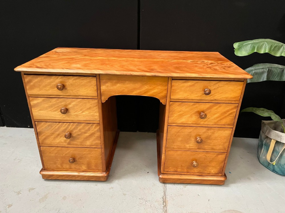 A Victorian satin birch pedestal writing desk featuring eight drawers with turned wooden knobs and an arched central kneehole. View XIV