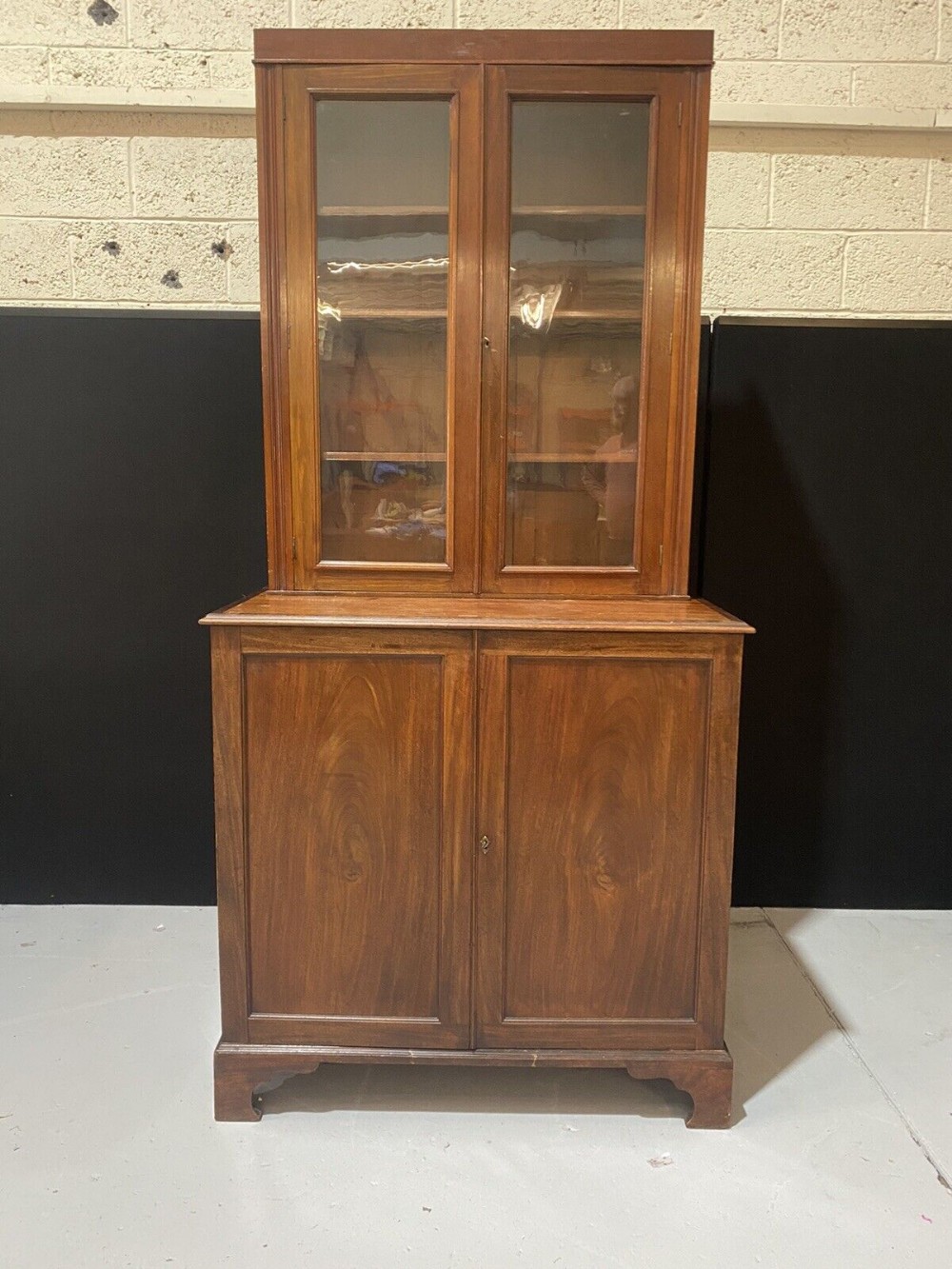 A tall mahogany library bookcase featuring two upper glazed doors and two flame mahogany panelled lower cupboard doors.