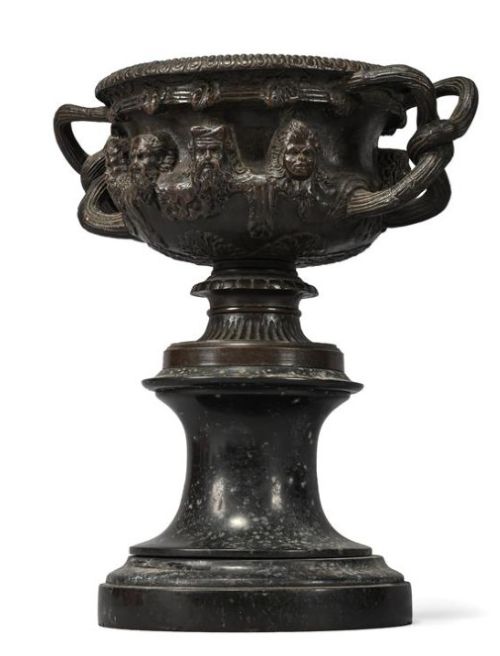 fig 1. A pair of nineteenth-century patinated bronze Warwick vases with classical relief masks and woven handles, resting on black marble socles.