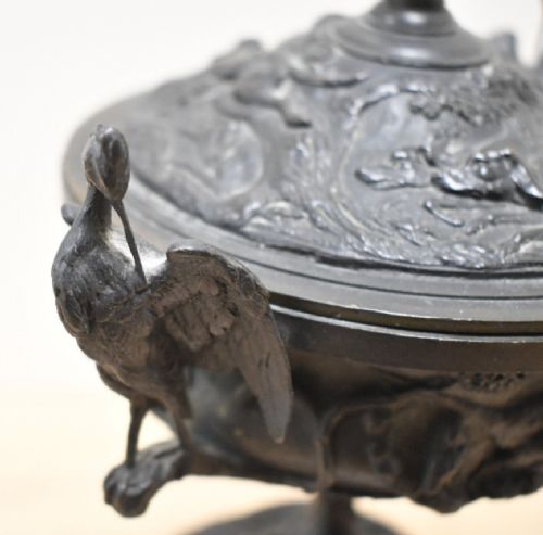 A pair of dark patinated bronze covered urns featuring relief-sculpted avian motifs and stork-shaped handles and finials on tiered bases. View XII