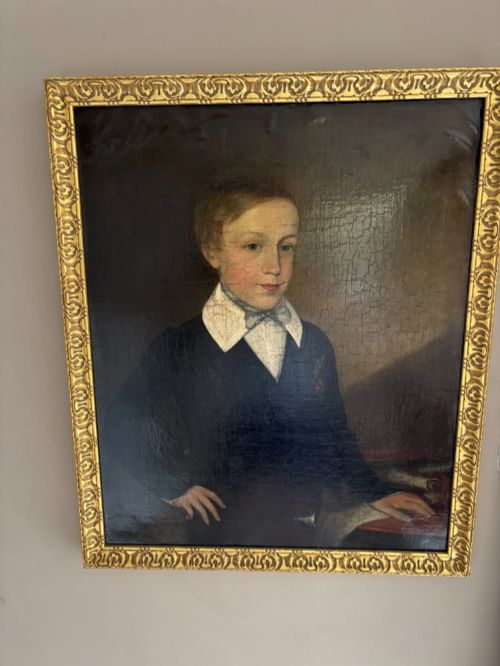 fig 1. An antique oil portrait depicting a young male scholar in a dark blue coat and white collar, set in a gilded ornate frame.