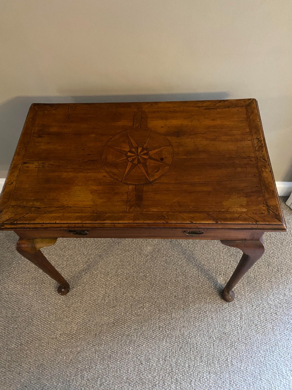 A Georgian fruitwood side table featuring cabriole legs with pad feet, a single drawer with brass handles, and a central star compass inlay on the tabletop. View VI