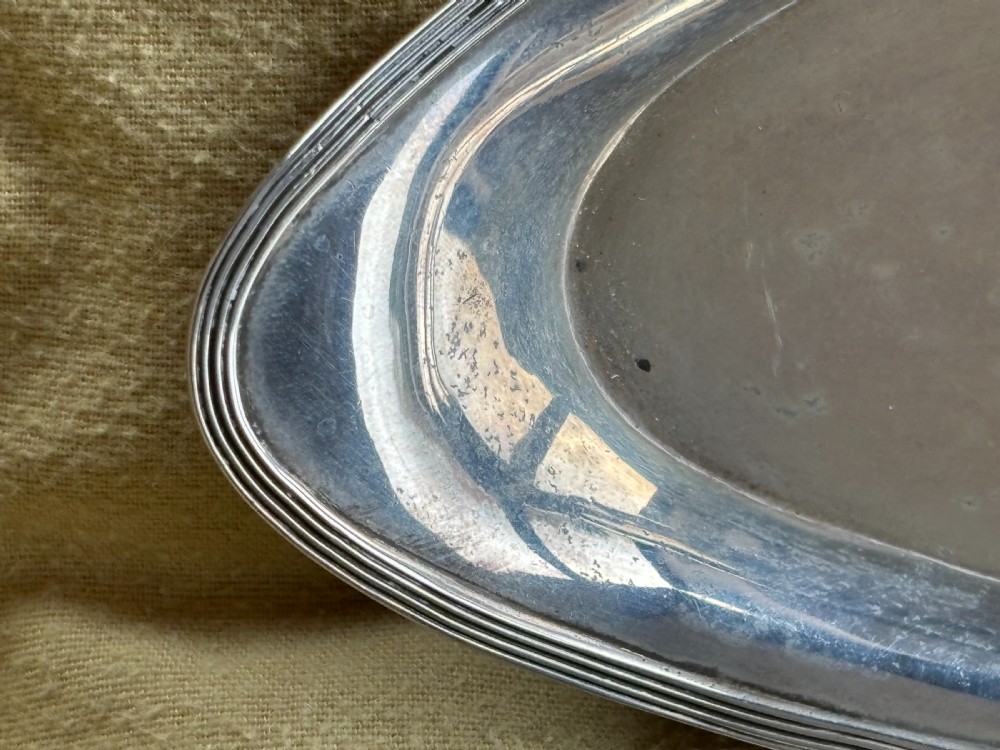 A George III sterling silver oval tray displaying visible British hallmarks stamped on its smooth inner rim. View III