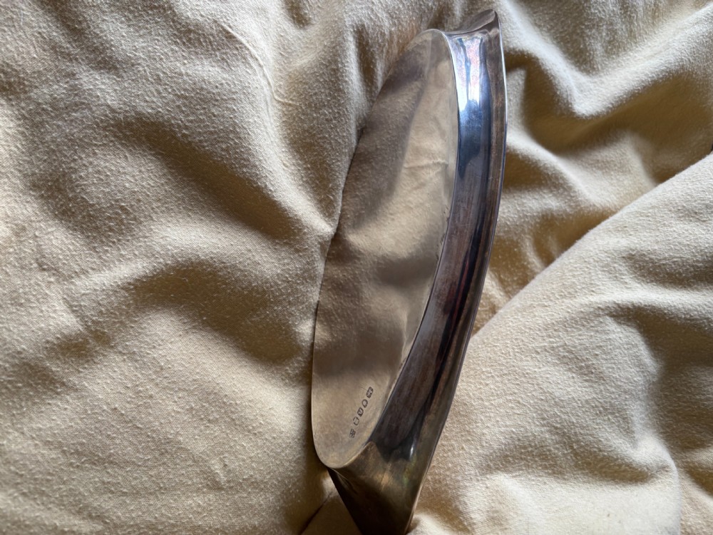 A George III sterling silver oval tray displaying visible British hallmarks stamped on its smooth inner rim. View V