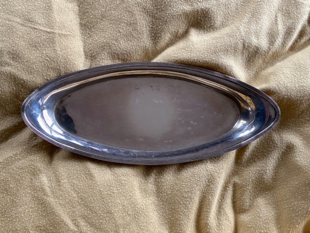 A George III sterling silver oval tray displaying visible British hallmarks stamped on its smooth inner rim. View VI
