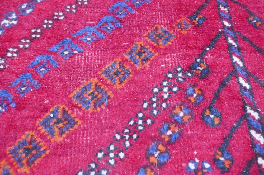 A rectangular hand-woven Persian wool carpet featuring a red stepped diamond centre, indigo blue spandrels, and geometric tribal borders. View VI