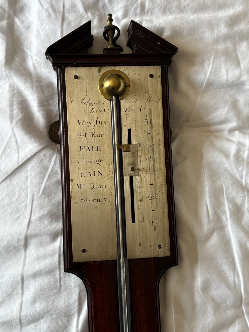 A late 18th-century Georgian mahogany stick barometer featuring a broken pediment top with a brass finial and an engraved silvered brass dial plate. View IV