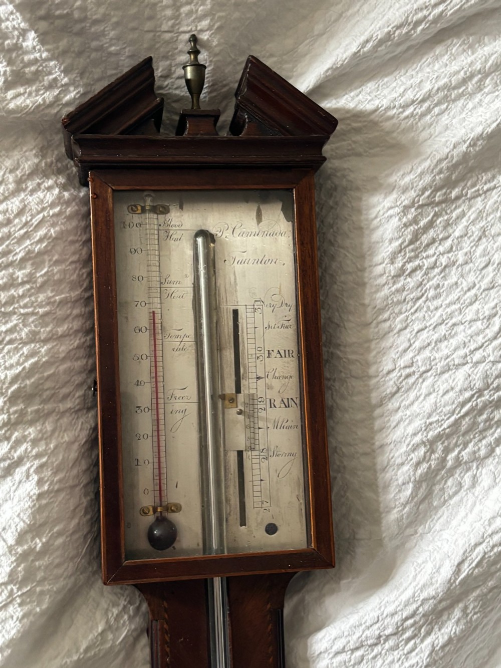 A Regency mahogany stick barometer featuring a pediment top, central mercury tube, thermometer, and an engraved silvered brass scale signed P. Caminada Taunton. View VI