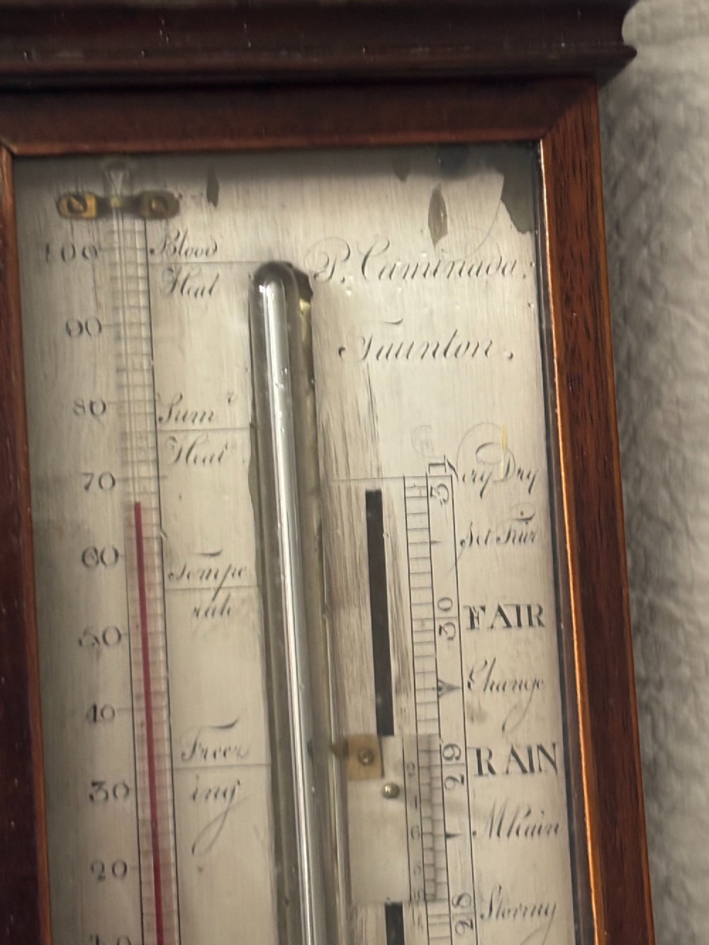 A Regency mahogany stick barometer featuring a pediment top, central mercury tube, thermometer, and an engraved silvered brass scale signed P. Caminada Taunton. View VIII