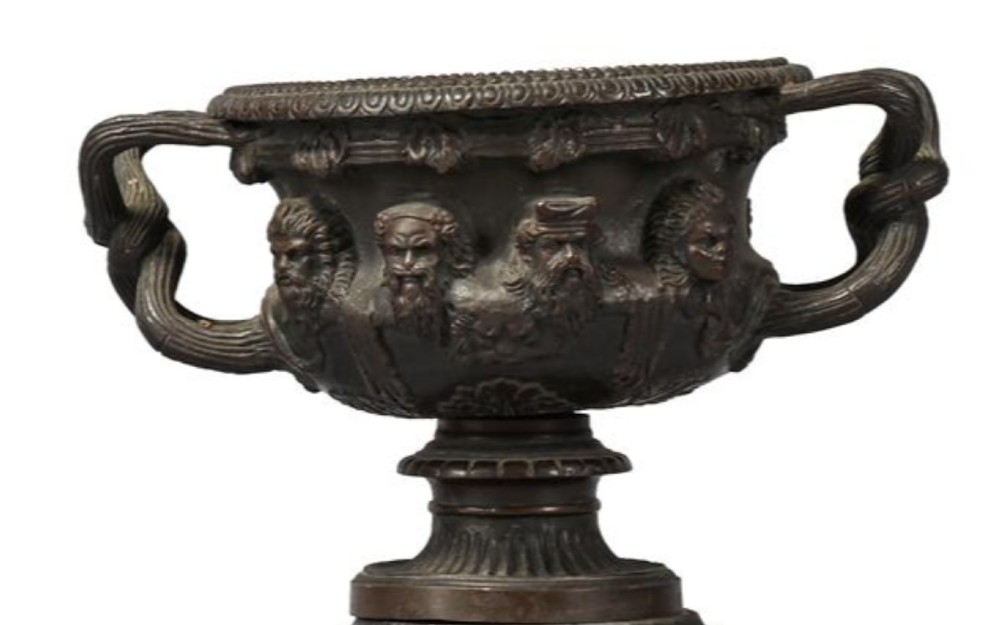 A pair of nineteenth-century patinated bronze Warwick vases with classical relief masks and woven handles, resting on black marble socles. View IV
