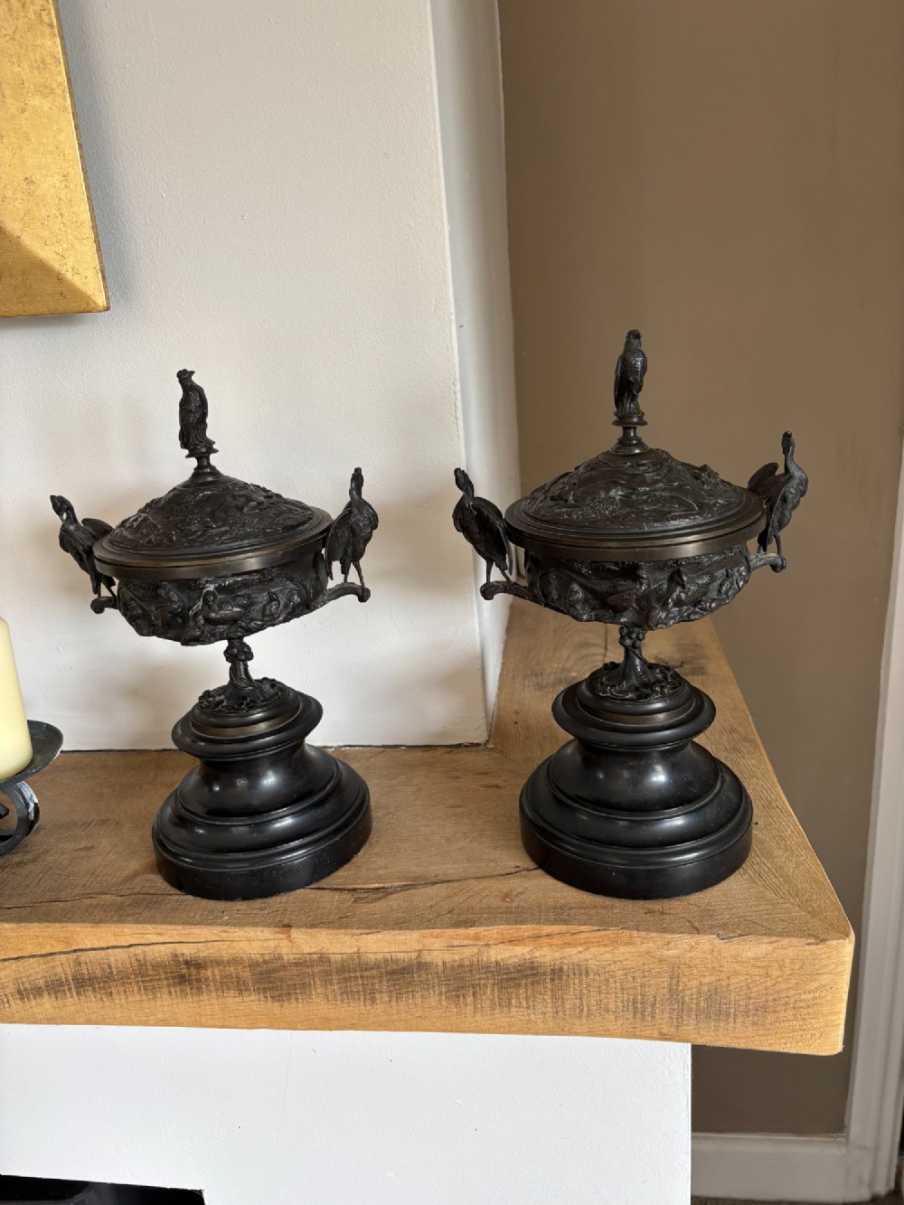 A pair of dark patinated bronze covered urns featuring relief-sculpted avian motifs and stork-shaped handles and finials on tiered bases. View III