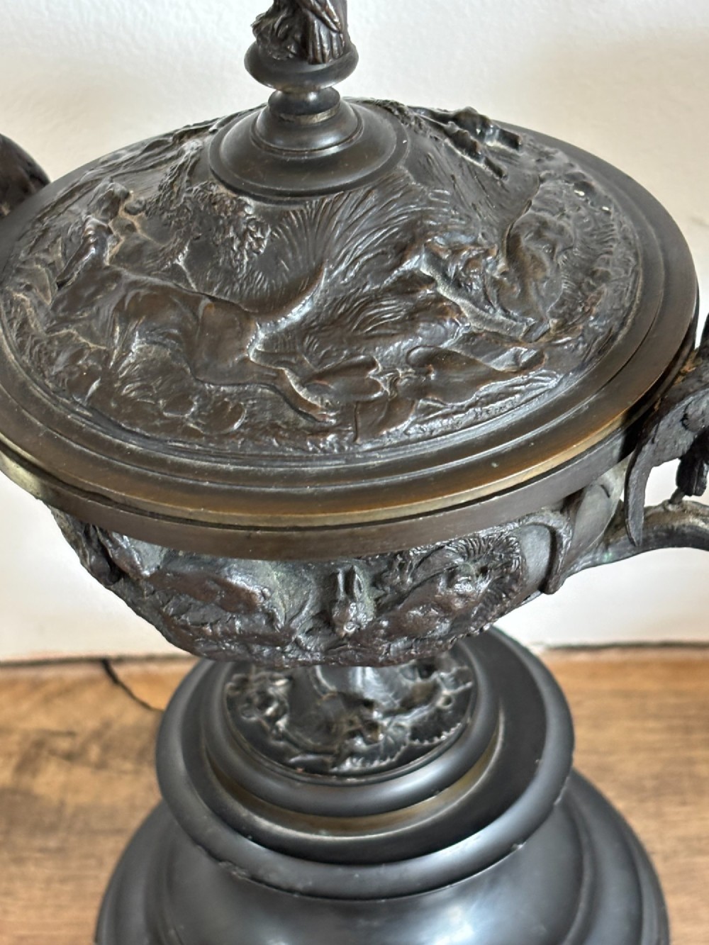 A pair of dark patinated bronze covered urns featuring relief-sculpted avian motifs and stork-shaped handles and finials on tiered bases. View VIII