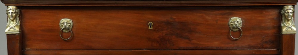 An early nineteenth-century French Empire mahogany commode featuring three drawers with brass lion-mask ring handles, gilt female caryatid mounts at the upper corners, a dark veined marble top, and sculpted paw feet. View II