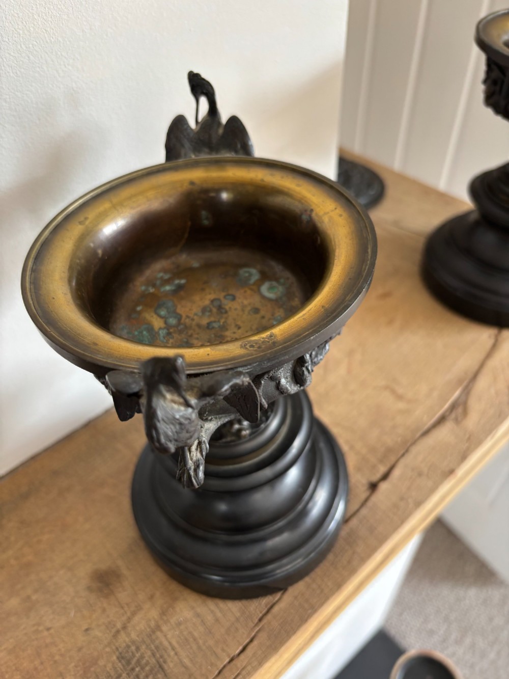 A pair of dark patinated bronze covered urns decorated with relief bird motifs and topped with stork finials on stepped pedestal bases. View V