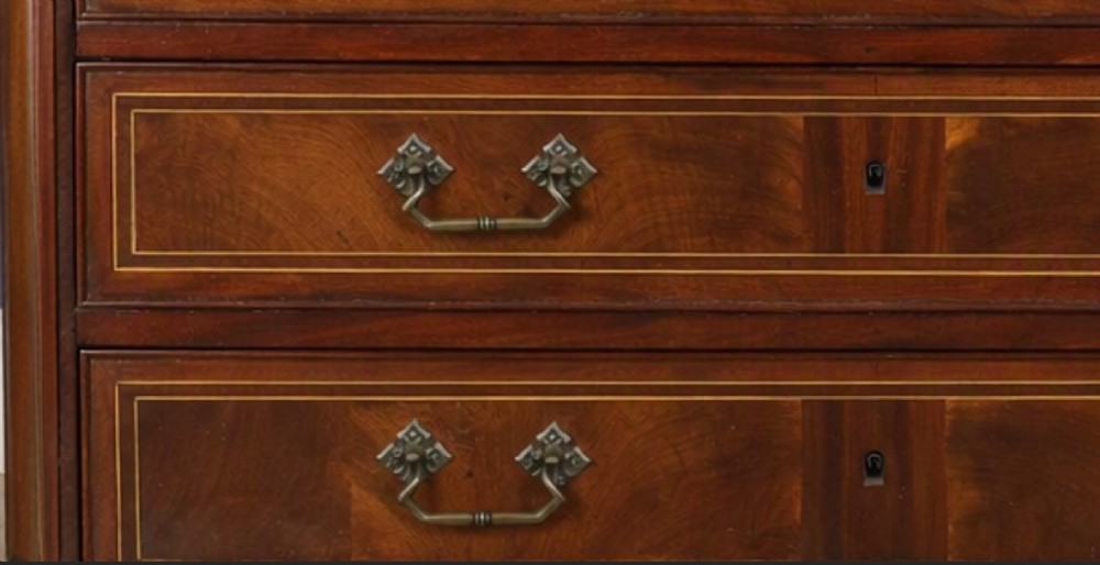 A late eighteenth-century French walnut and fruitwood commode featuring three drawers with string inlay, brass handles, and a grey marble top. View II