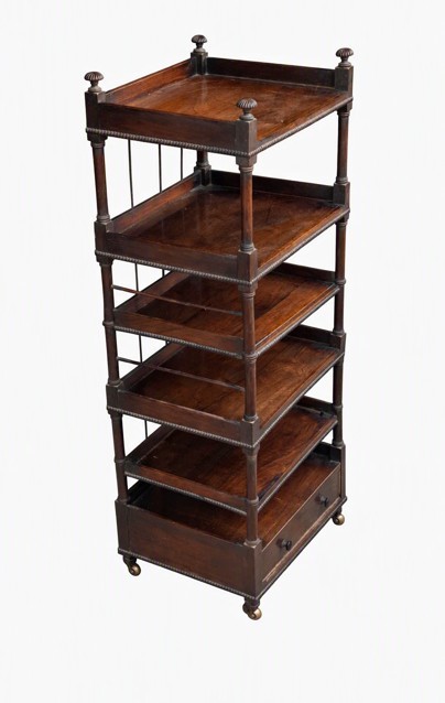 A tall six-tier dark rosewood Regency whatnot featuring turned corner pillars, beaded shelf borders, a base drawer, and castors. View II